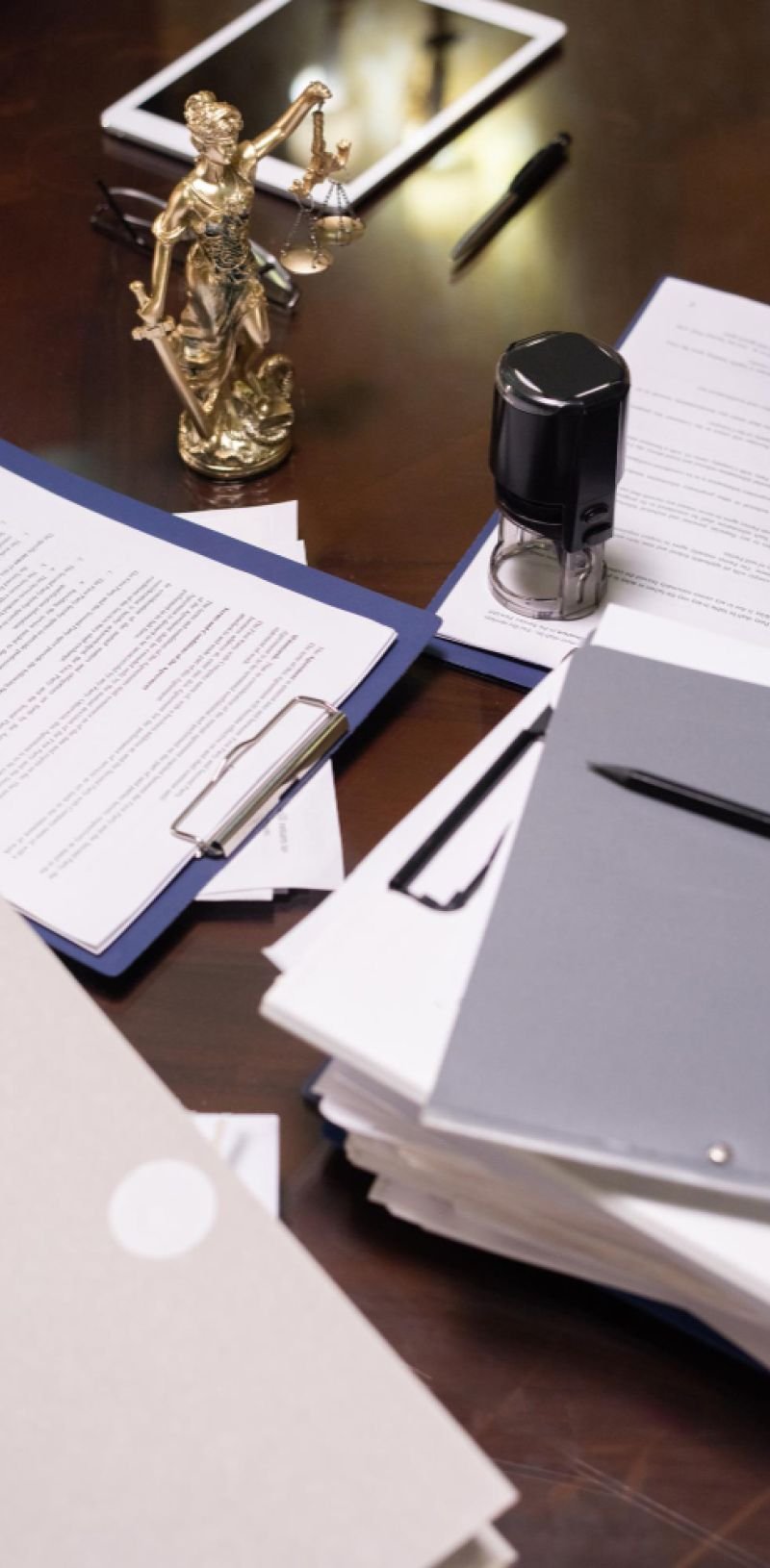 Mesa com documentos, um carimbo e a estátua da Deusa Têmis 
